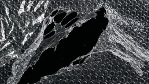 Torn Bubble Wrap with a Hole Revealing a Black Background Stock Footage 333350193