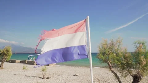 Torn dutch flag waving on a windy day at the beach Stock Footage 289663337