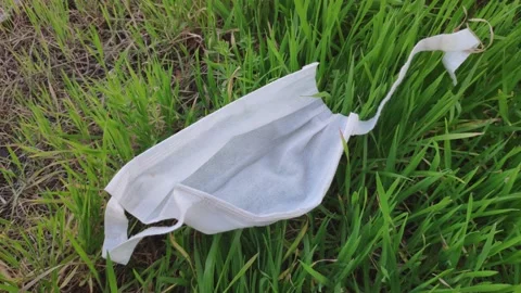 Torn face mask thrown away on the grass Stock Footage 149387530