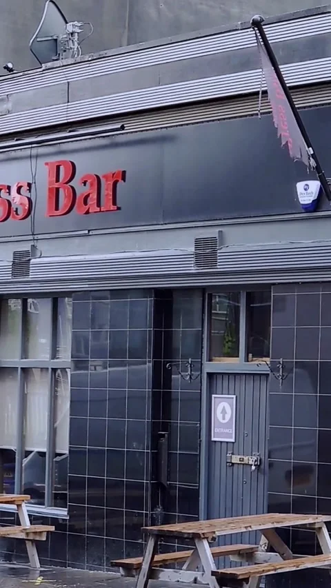 A torn flag in the wind outside a bar - Vertical Video Stock Footage 200400597