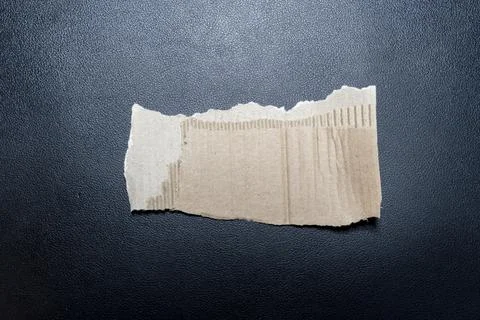 A torn piece of cardboard on a black background showcases texture and layering. Stock Photos