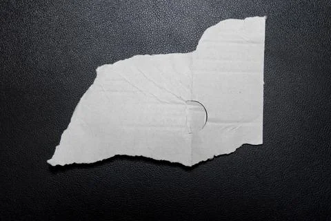 A torn piece of white paper displaying a circular hole, set against a dark Stock Photos