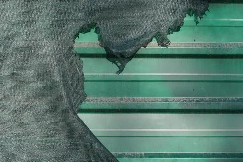 Torn plastic protective net over a metal fence Foto stock