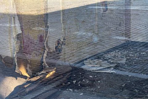 Torn poster and street reflection on cobblestone pavement Stock Photos