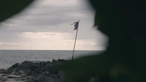 Torn Puerto Rican flag at beach on stormy day in Puerto Rico Stock Footage 157402216