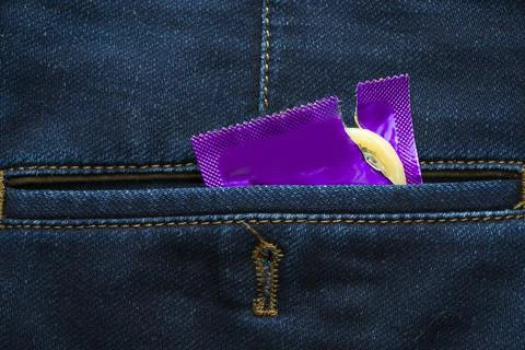 Torn ready to use condom in the pocket of blue jeans, protect yourself, use a Stock Photos