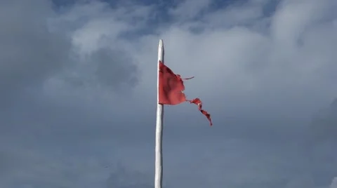 Torn red Isle of Man flag waving in the wind against clouded sky Stockbeeldmateriaal 43171784