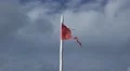 Torn red Isle of Man flag waving in the wind against clouded sky HD Footage