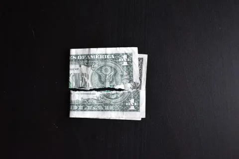 Torn ripped devalued one dollar bank note on a black background. close-up of  Stock Photos