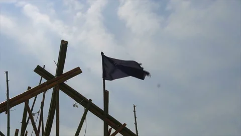 Torn tattered pirate flag waves in the wind tied to rigging on tall ship Stock-Footage 94137135