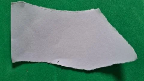 Torn white paper scrap placed on a vibrant green background surface Stock Photos