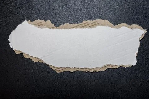 A torn white paper sheet with a rough edge, positioned against a dark 写真素材