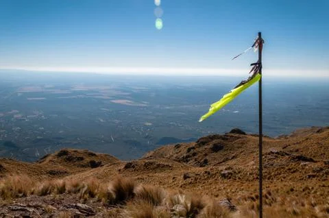 Torn yellow flag fluttering in deep blue sky over the top of brownish steppe Stock Photos