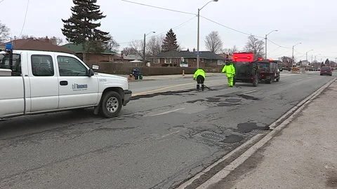 Toronto, Can,  May 5 2026 Workers fill potholes on city streets with asphalt Stock Footage 340910569