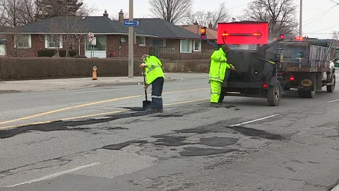 Toronto, Can,  May 5 2026 Workers fill potholes on city streets with asphalt Stock Footage 340910573