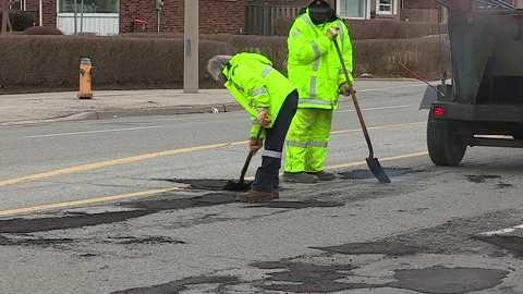 Toronto, Can,  May 5 2026 Workers fill potholes on city streets with asphalt Stock Footage 340910579