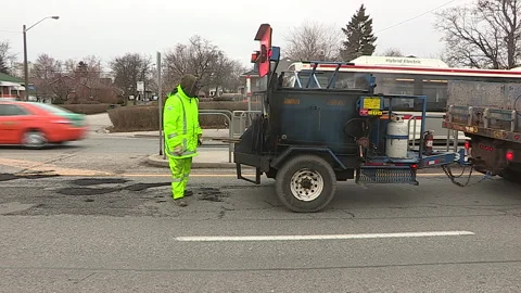 Toronto, Can,  May 5 2026 Workers fill potholes on city streets with asphalt Stock Footage 340910584