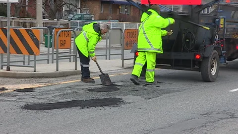 Toronto, Can,  May 5 2026 Workers fill potholes on city streets with asphalt Stock Footage 340910594