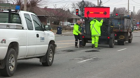 Toronto, Can,  May 5 2026 Workers fill potholes on city streets with asphalt Stock Footage 340910595