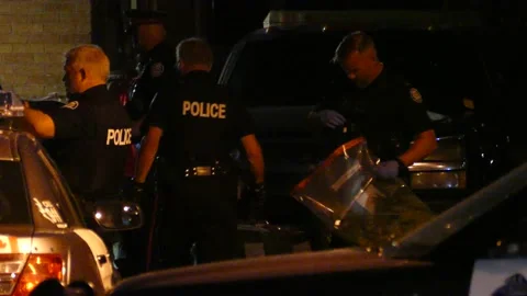 Toronto cops seizing weed in large transparent bags in driveway at night Video stock 136438451