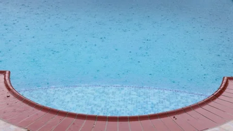 Torrential rain droplets falling on the surface of a swimming pool. 4K. Stock Footage 223661597
