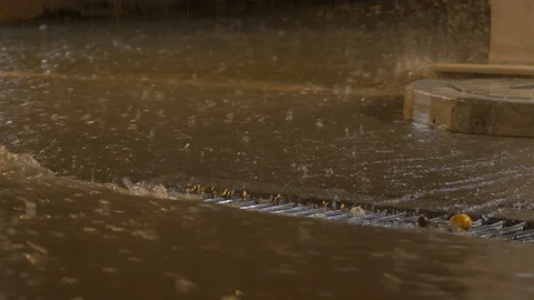 Torrential rainfall flowing down street into drain Stock Footage 123747103