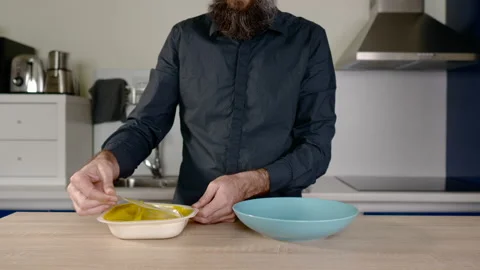 Torso of a man with a beard opening a container of ready made food and throwi Stock Footage 131228819