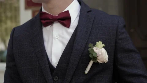 Torso of man in blue suit,red bow tie.Side loop of groom from fresh flowers. Stock Footage 132096430