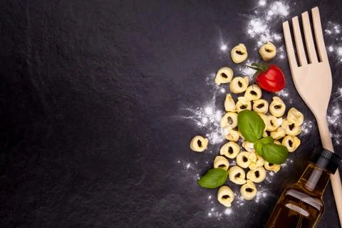 Tortellini and flour on a black stone plate. Stock Photos