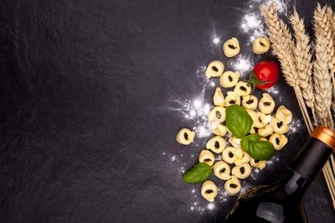 Tortellini and flour on a black stone plate. Stock Photos