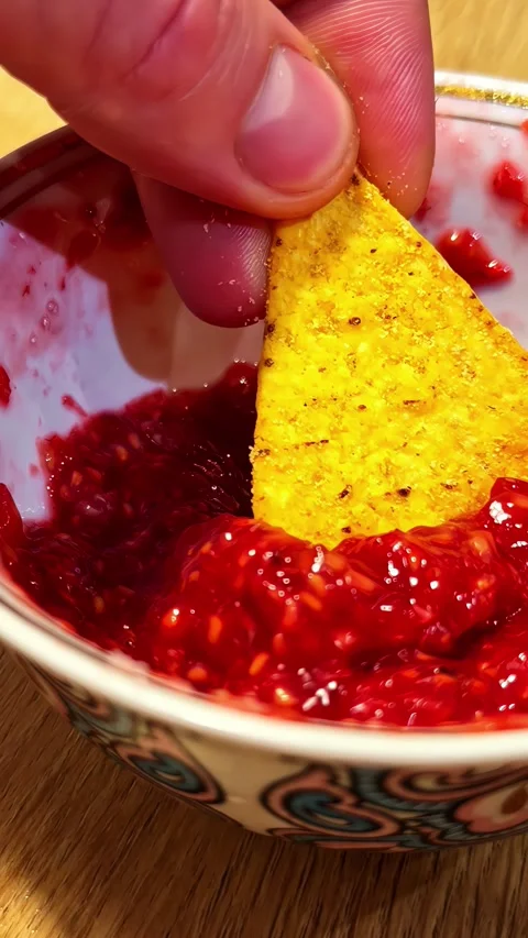 Tortilla chip dipping into rich red tomato salsa sauce inside an ornamental Stock Footage 337183211
