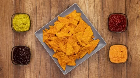 Tortilla chips filling a rotating rectangular plate with assorted sauces Stock-Footage 124232345