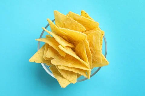 Tortilla chips (nachos) in glass bowl on light blue background, top view Stock Photos