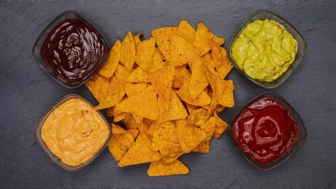 Tortilla chips piling surrounded by a variety of sauces - stop motion Video stock 124612011