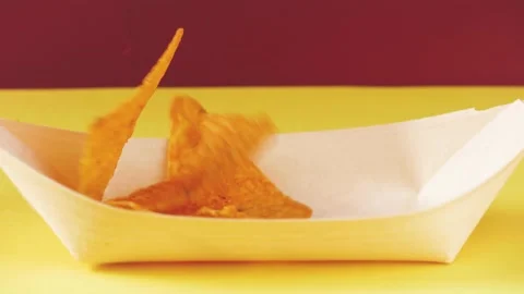Tortillas chips falling down on bamboo party dish. red background. Chips  Stock Footage 149663311