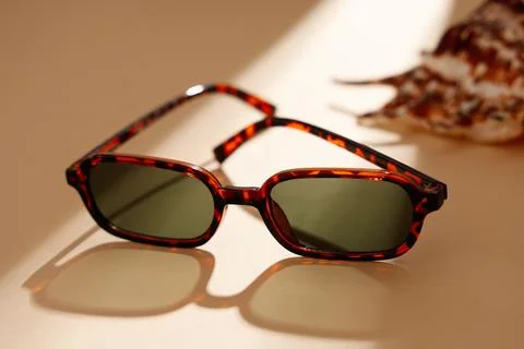 Tortoiseshell sunglasses with seashell on beige surface 写真素材