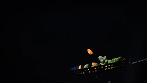Tossed vegetables in the pan, flying ingredients of a vegetarian dish. Video stock 219855956