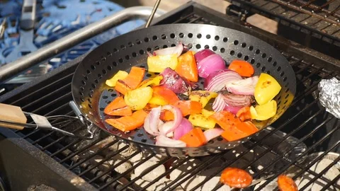 Tossing vegetables in a pan on a BBQ Stock Footage 115058704