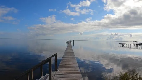 Total reflection of sky on water surrounding long dock Stock Footage 232909664