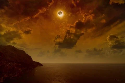 Total solar eclipse in dark red sky above sea and mountains Stock-Fotos