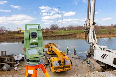Total station in front of Mobile crane and drilling machine working togethe.. Stock Photos