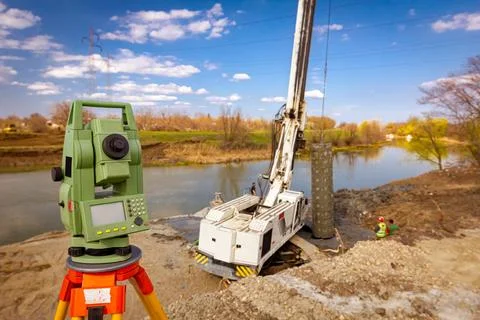 Total station in front of Mobile crane and drilling machine working togethe.. Stock Photos