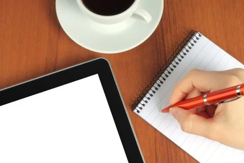 Touch screen device, notepad, writing hand and cup of coffee on wooden backgr Stock Photos