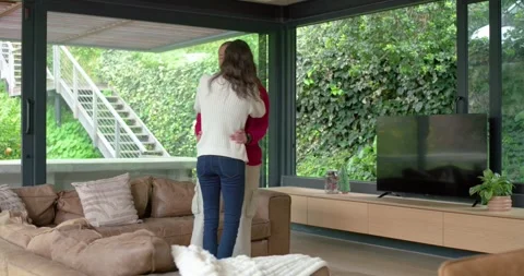 Touch sparking diverse couple swaying, lifting in living room with garden view Stock Footage 344316991