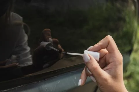 Touching up a body car with a small brush by a young woman Stock Photos