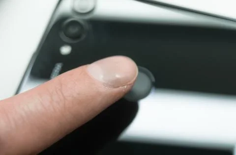 Touching the fingerprint sensor on the back of the smartphone. Mobile phone Stock Photos