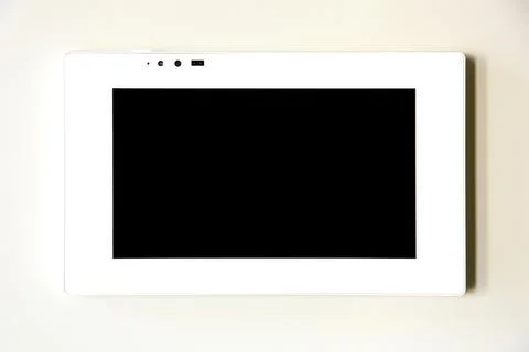 Touchscreen control tablet smart home in white on a beige wall, close up. Stock Photos