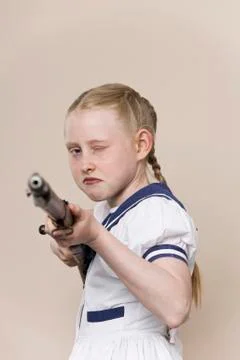 A tough girl wearing a sailor dress aiming a rifle at the camera Фото