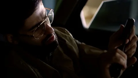 Tough guy is checking his gun inside a dark car, loading small pistol and 動画素材 87996525