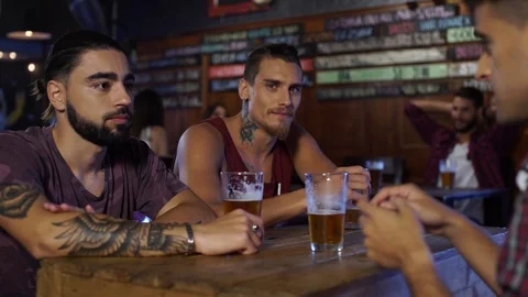 Tough guy drinking a pint of beer while looking at the camera in a bar Stock Footage 114447267